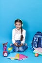 Back to school. Portrait of school girl in glasses sit floor on blue background. Royalty Free Stock Photo