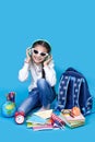 Back to school. Portrait of school girl in glasses sit floor on blue background. Royalty Free Stock Photo