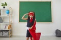 Back to school. Positive schoolgirl superhero standing posing in class.