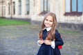 Back to school. Pupil of primary school. Girl with backpack near building outdoors. Beginning of lessons. First day of fall. Happy Royalty Free Stock Photo