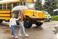 Back to school. Pupils of primary school near school bus. Happy children ready to study. little girl with mom going to Royalty Free Stock Photo