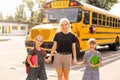 Back to school. Pupils of primary school near school bus. Happy children ready to study. little girls with mom going to Royalty Free Stock Photo