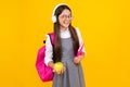 Back to school. School child, teenage student girl with bagpack hold apple and book isolated on yellow. Happy face