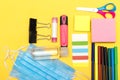 Back to school, school supplies with medical face mask on a yellow background. Protection of schoolchildren and student.