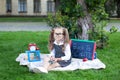 Back to school. schoolgirl with glasses holds a magnifying glass. A little girl sits on the grass near the school with books, a sc Royalty Free Stock Photo