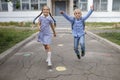 Back to school. Siblings with backpacks running from the school after their first offline day Royalty Free Stock Photo