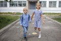 Back to school. Siblings with backpacks running from the school after their first offline day Royalty Free Stock Photo