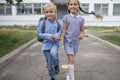 Back to school. Siblings with backpacks running from the school after their first offline day Royalty Free Stock Photo