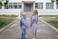 Back to school. Siblings with backpacks staying near school doors before their first offline day Royalty Free Stock Photo