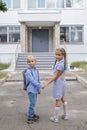 Back to school. Siblings with backpacks staying near school doors before their first offline day Royalty Free Stock Photo