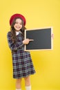 Back to school. Small school child pointing finger at blank blackboard on yellow background. Cute little schoolgirl with Royalty Free Stock Photo