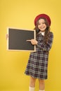 Back to school. Small school child pointing finger at blank blackboard on yellow background. Cute little schoolgirl with Royalty Free Stock Photo