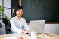 Portrait of young woman teacher with laptop at desk in classroom Royalty Free Stock Photo