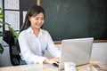 Portrait of young woman teacher with laptop at desk in classroom Royalty Free Stock Photo