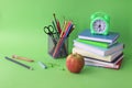 Back to school, stationery, alarm clock, stack of books, apple on bright background Royalty Free Stock Photo