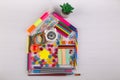 Back to school study concept. Toy house made of office stationery. Clock, flower, pins, pencil, marker, pen, chalk, sticker, Royalty Free Stock Photo