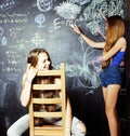 Back to school after summer vacations, two teen girls in classroom with blackboard painted together Royalty Free Stock Photo