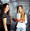 Back to school after summer vacations, two teen real girls in classroom with blackboard painted together, lifestyle Royalty Free Stock Photo