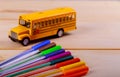 Back to school supplies colored pencils toy yellow school bus on wooden background Royalty Free Stock Photo