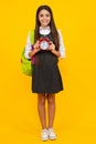 Back to school. Teenage school girl with bag hold clock alarm, time to learn. Schoolgirl on isolated yellow background Royalty Free Stock Photo