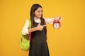 Back to school. Teenage school girl with backpack hold clock alarm, time to learn. Schoolgirl on isolated yellow Royalty Free Stock Photo