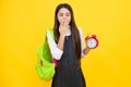 Back to school. Teenage school girl with bag hold clock alarm, time to learn. Schoolgirl on isolated yellow background Royalty Free Stock Photo