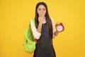 Back to school. Teenage school girl with bag hold clock alarm, time to learn. Schoolgirl on isolated yellow background Royalty Free Stock Photo