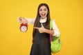 Back to school. Teenager schoolgirl with bag hold clock alarm, time to learn. School children on isolated yellow Royalty Free Stock Photo