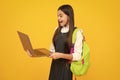Back to school. Teenager schoolgirl hold notebook laptop. School children on isolated yellow studio background. Excited Royalty Free Stock Photo