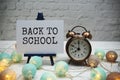 Back to School text and alarm clock on white brick wall and wooden background Royalty Free Stock Photo