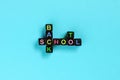 Back to school text from colorful letters on black cubes laid out in form of crossword puzzle, blue background. Concept education Royalty Free Stock Photo