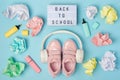 Back to school text on lightbox. Headphones, pink shoes, colored crumpled paper balls, marker on blue background. Education