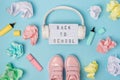 Back to school text on lightbox. Headphones, pink shoes, colored crumpled paper balls, marker on blue background