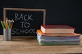 Back to school text written on chalkboard with book stack and pen holder