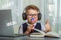 Back to school. Thinking child doing homework online with smartphone. Pupil in headphones. Learn English. Royalty Free Stock Photo