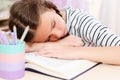 Back to school. Tired little child girl sleeping on the desk while doing homework Royalty Free Stock Photo