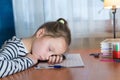Back to school. Tired little child girl sleeping on the desk while doing homework. Education learning concept