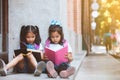 Two cute asian pupil girls reading a book together in the school with fun and happiness