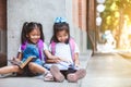 Two cute asian pupil girls reading a book together in the school with fun and happiness