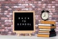 Back to school words on a letter board with books and vintage alarm clock against brick wall background Royalty Free Stock Photo