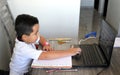 Back to school, 7 year old Latino boy in online home classes with laptop and school supplies Royalty Free Stock Photo