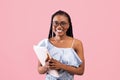 Back to school. Young black female student with book and notebooks smiling at camera on pink studio background Royalty Free Stock Photo