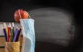 Back to virtual school background concept with stack of books, pencil, apple with face mask Royalty Free Stock Photo