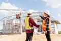 Back two architect and client discussing help create plan with blueprint home building at construction site Royalty Free Stock Photo