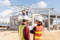 Back two architect and client discussing help create plan with blueprint home building at construction site Royalty Free Stock Photo