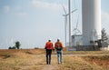 Back of two Caucasian engineers or technicians walk to cluster of windmill or wind turbine for maintenance or manage system in