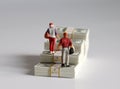 The back of two miniature people walking on a pile of banknotes stacked in the shape of a staircase.