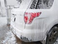 The back of the very dirty white SUV, doused with shampoo and foam, stands in the box