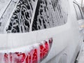 The back of the very dirty white SUV, doused with shampoo and foam, stands in the box