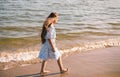 Back view of little girl with long hair in white dress walking on tropical beach vacation Royalty Free Stock Photo